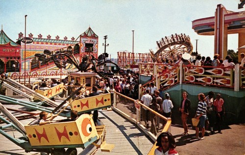 A bustling amusement park scene with rides, colorful attractions, and a crowd of people enjoying the festivities.