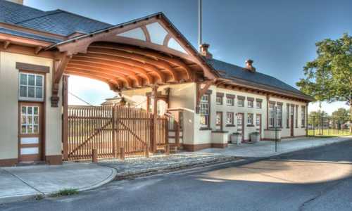 Historic train station with a wooden canopy and decorative architecture, set against a clear sky.