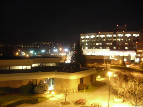Nighttime view of a campus with buildings, lights, and trees, showcasing a serene urban landscape.