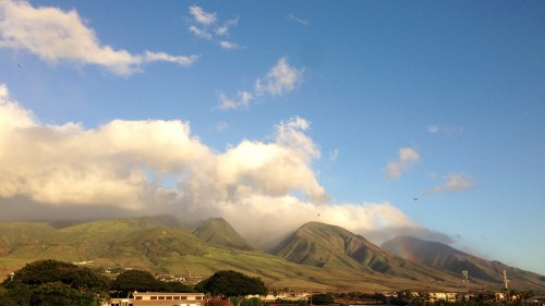 Lush green mountains under a blue sky with scattered clouds, capturing a serene landscape.