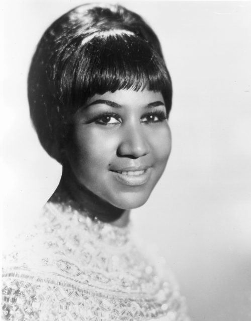 Black and white portrait of a smiling woman with a short hairstyle, wearing a sparkling top.