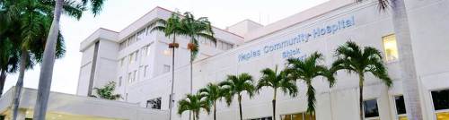Exterior view of Health Community Hospital, featuring palm trees and a modern architectural design.