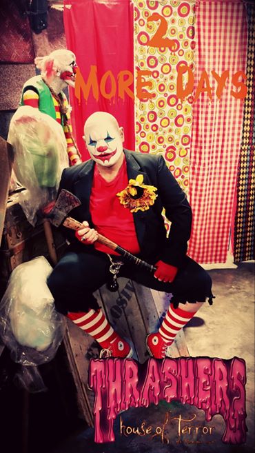 A clown with an axe sits in front of colorful backdrops, promoting "2 More Days" for Thrashers House of Terror.