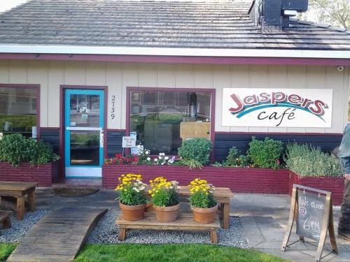A cozy café with a colorful sign, flower pots, and outdoor seating, featuring a welcoming entrance.