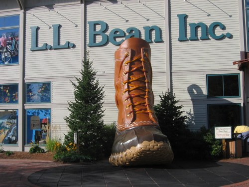 Giant boot sculpture in front of L.L. Bean store, surrounded by greenery and featuring the company name above.