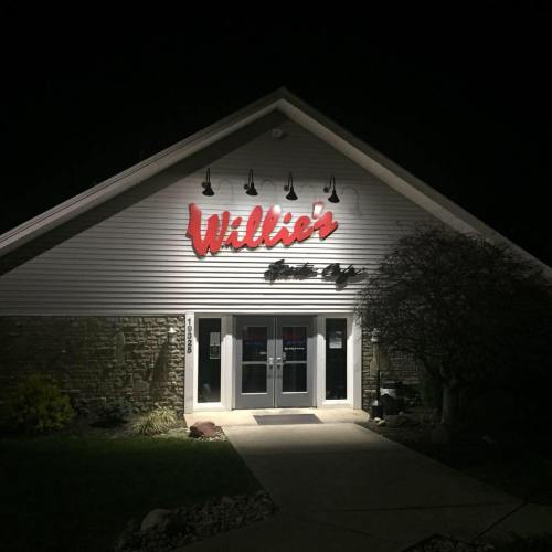 Exterior of Willie's Sports Bar at night, featuring a lit sign and entrance with double doors.