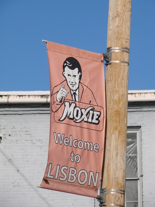 A banner reading "Welcome to Lisbon" with a vintage illustration of a man pointing, featuring the word "Moxie."