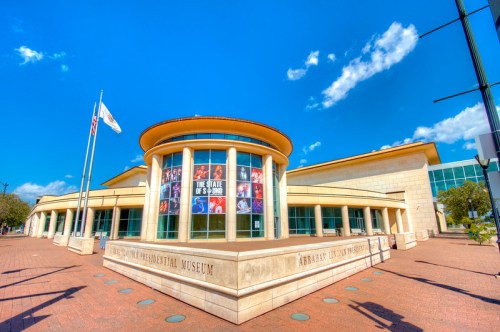 Exterior view of the Abraham Lincoln Presidential Museum, featuring columns and a vibrant blue sky.