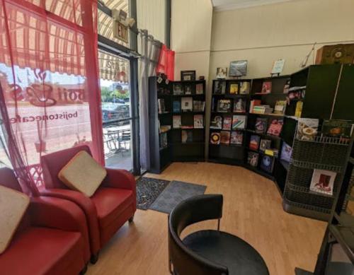 Cozy interior of a café with red chairs, a bookshelf filled with magazines, and a welcoming atmosphere.