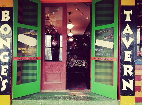 Colorful entrance to Bongo's Tavern, featuring green doors and vintage signage, inviting patrons inside.