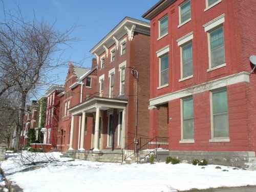 A row of historic brick houses with snow on the ground, under a clear blue sky.