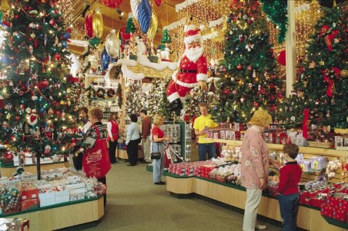 A festive store filled with Christmas decorations, trees, and shoppers admiring holiday items.