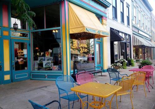 Colorful outdoor seating in front of a café with a bright yellow awning and vibrant storefront.