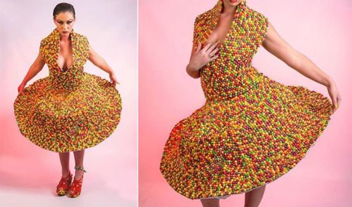 A model poses in a vibrant, colorful dress made of candy, showcasing a playful and creative fashion design.