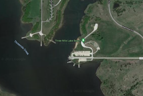 Aerial view of Three Mile Lake Beach, featuring a boat ramp and surrounding greenery along the water's edge.