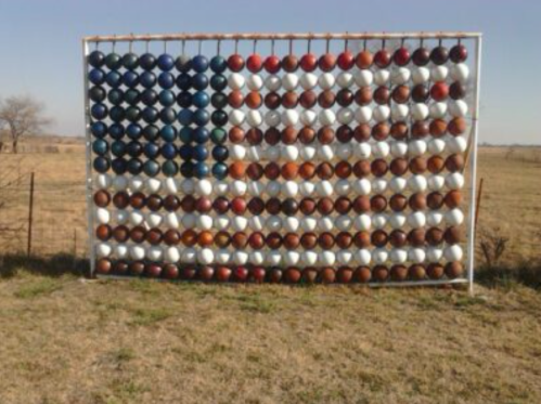 A large display of painted bowls arranged to resemble the American flag, set against an open field.