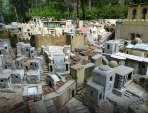 A detailed miniature model of a historic city with intricate buildings and staircases set in a natural landscape.