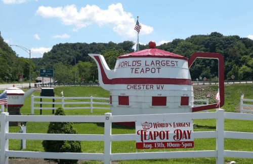 A large teapot structure with a sign reading "World's Largest Teapot" in Chester, WV, surrounded by greenery.