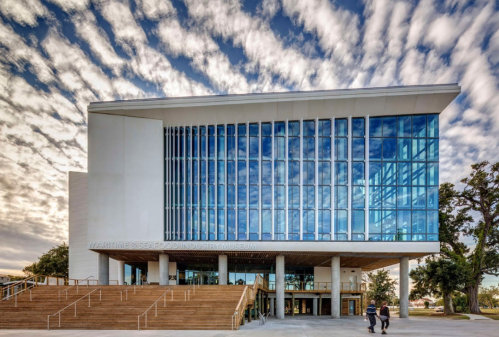 Modern building of the Maritime & Seafood Industry Museum with large glass windows and a dramatic sky in the background.
