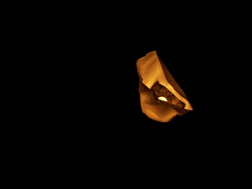 A glowing lantern floating against a dark background, casting a warm light.