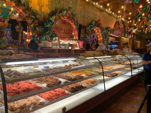 A colorful display of various pastries and sweets in a festive bakery, adorned with lights and decorations.