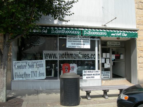 Exterior of the Mothman Museum and Gift Shop, featuring signs and banners about the museum and its admission details.