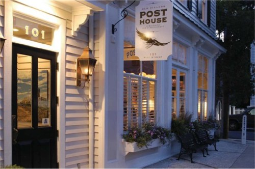 Exterior of the Post House restaurant, featuring a sign, lantern, and flower boxes, in a charming, well-lit setting.