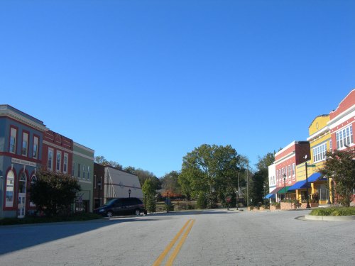 A quiet street scene with colorful buildings on either side under a clear blue sky.