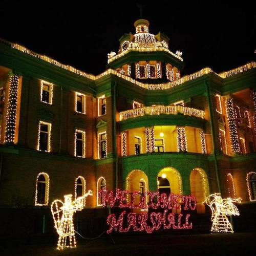 A beautifully lit building at night, adorned with festive lights and a sign reading "Welcome to Marshall."