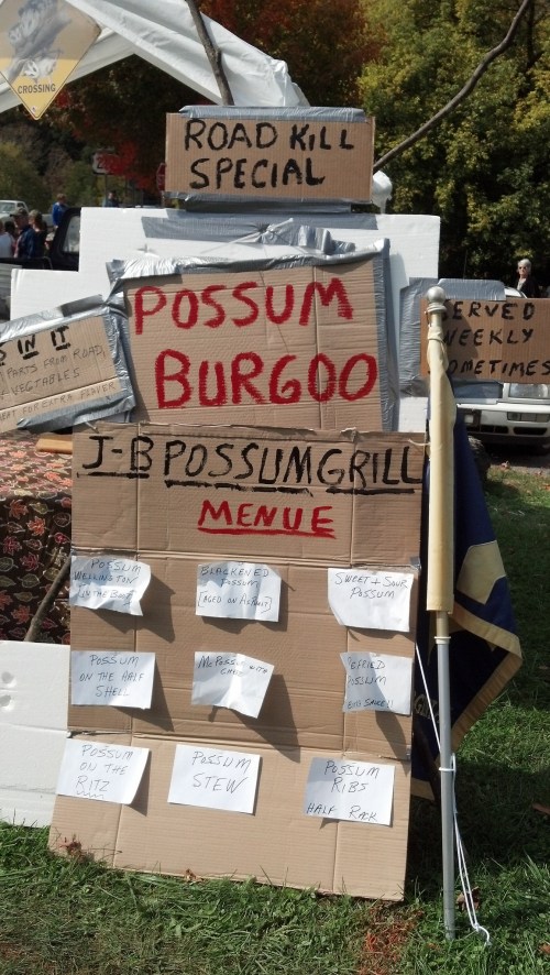 Signboard displaying a menu for "Possum Burgoo" and "J-B Possum Grill," featuring various possum dishes.
