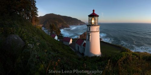 A scenic lighthouse on a cliff overlooking the ocean at sunset, surrounded by lush greenery and rolling hills.