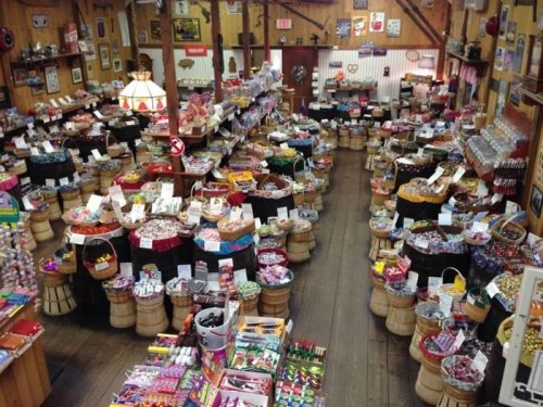 A colorful candy store filled with various sweets displayed in baskets and on tables, creating a vibrant atmosphere.