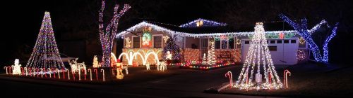 A house decorated with colorful Christmas lights, featuring trees, candy canes, and festive figures.