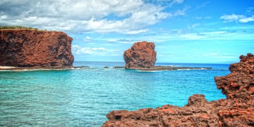 Scenic view of rocky formations in turquoise water under a partly cloudy sky.
