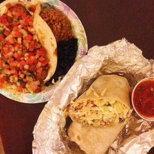 A plate with tacos, rice, beans, and a wrapped burrito with salsa on the side.