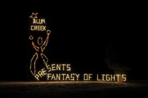 A festive display of lights reading "Alum Creek Presents Fantasy of Lights" against a dark background.