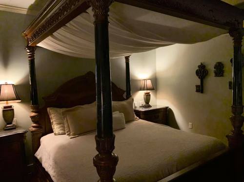 A cozy bedroom featuring a four-poster bed, soft lighting, and elegant decor.