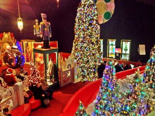 A festive indoor scene featuring a large Christmas tree, colorful decorations, and people enjoying the holiday atmosphere.