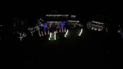 A beautifully decorated yard at night, featuring colorful holiday lights on trees and festive displays.