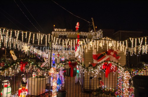 A festive display of Christmas lights, inflatables, and decorations adorning a house and yard at night.