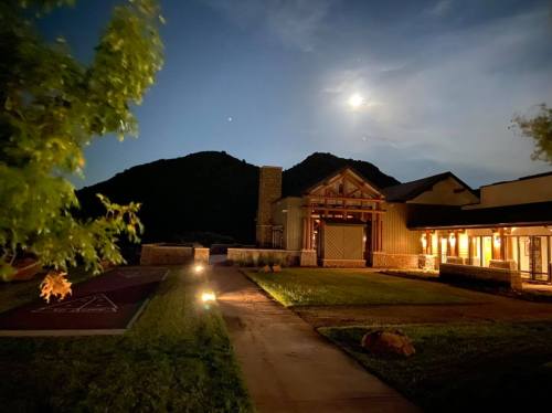 A serene night scene of a building with mountain backdrop, illuminated by moonlight and soft landscape lighting.