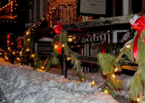 A snowy scene with festive garlands and lights adorning a railing, creating a cozy holiday atmosphere.