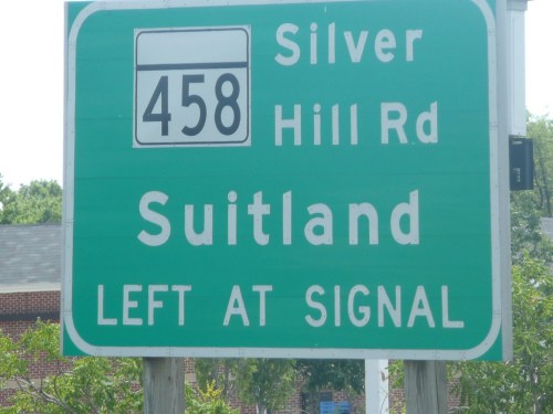 Green road sign indicating Silver Hill Rd, Suitland, with the number 458 and directions to turn left at the signal.