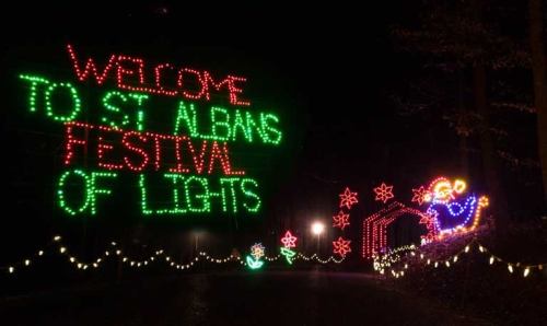 Colorful holiday lights display reading "Welcome to St. Alban's Festival of Lights" with festive decorations along a path.