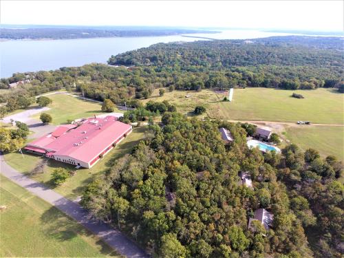 Aerial view of a large building surrounded by trees, with a lake and hills in the background.
