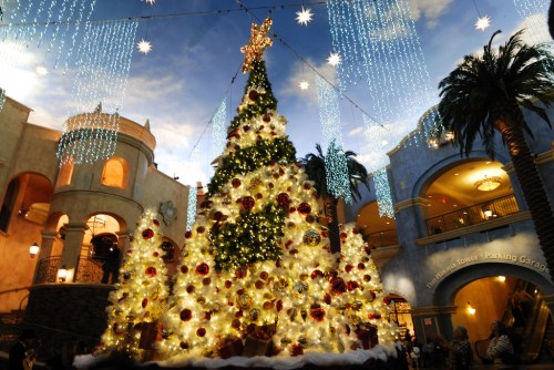 A beautifully decorated Christmas tree with lights and ornaments, surrounded by festive decorations and palm trees.