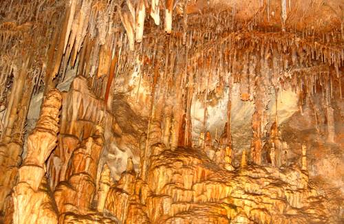 Stalactites and stalagmites in a colorful cave, showcasing intricate rock formations and textures.