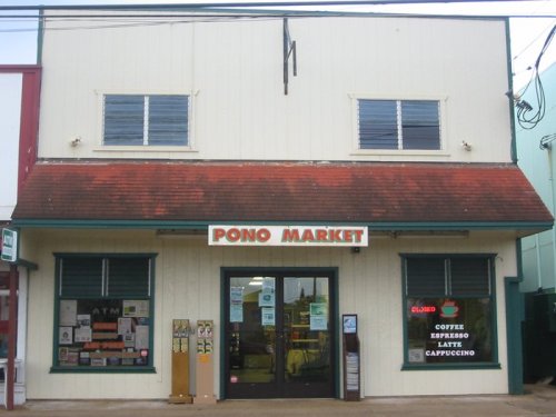 Exterior of Pono Market, a two-story building with a red roof, featuring a sign and various storefront displays.
