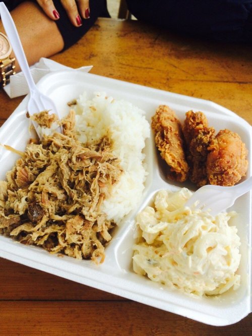 A food tray with rice, pulled meat, fried chicken, and macaroni salad, served with plastic utensils.