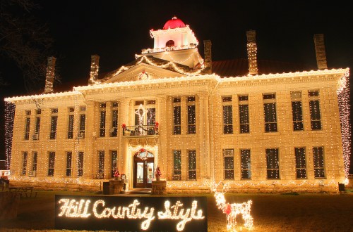 Historic building adorned with festive lights, featuring a red dome and a sign reading "Hill Country style."